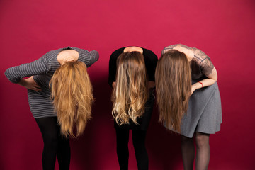 three girls bent over their hair covering their face