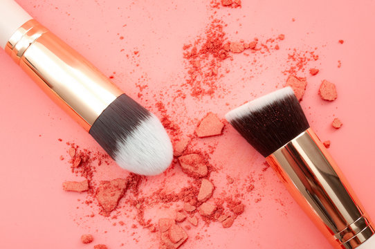 Female fashion and cosmetics, beauty products and makeup artist school concept theme with make up brushes in blush face powder isolated on pink background