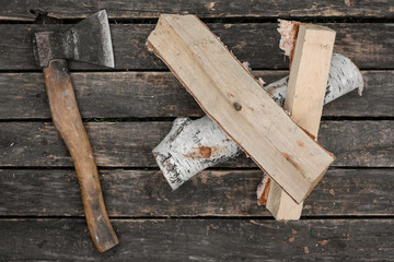 Hatchet and a wooden logs on a wooden floor background.