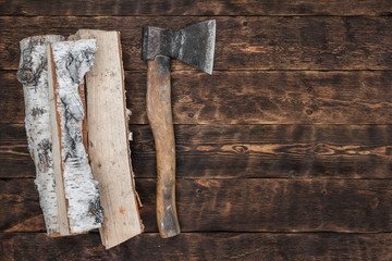 Hatchet and a wooden logs on a wooden floor background with copy space.