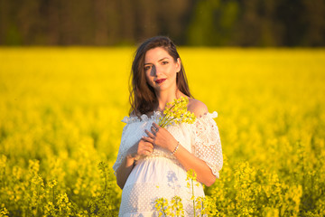 Naklejka na ściany i meble beautiful pregnant brunette Young beautiful pregnant woman touching her belly with love and care, making a heart shape.