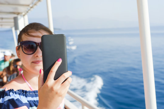 Young woman taking self portrait pictures while sailing on the ship on the sea summer holiday vacation