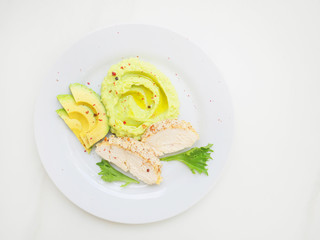 Healthy balanced lunch with baked chicken breast, avocado slices and mashed potato on white background, top view. 