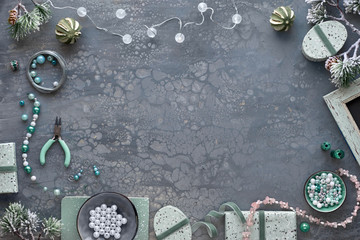 Making handmade jewelry for friends as Christmas gifts. Flat lay on dark textured background with...