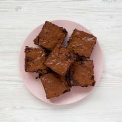 Homemade chocolate brownies on a pink plate on a white wooden background, top view. Flat lay,...