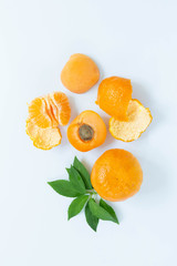 Close up of oranges and nectarines, peeled orange, white background, top view