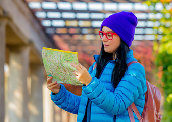 girl in blue jacket in red glasses at backpack with travel map