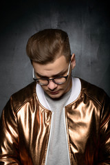 Fashion photo portrait of a young male man model posing in studio in modern trendy fashionable clothes on a grey background