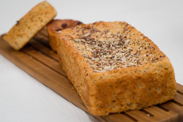 Homemade bread served on wooden table for breakfast. Healthy bakery concept. Bread with rye, sesame and wheat on top. Soft and spongy bread.