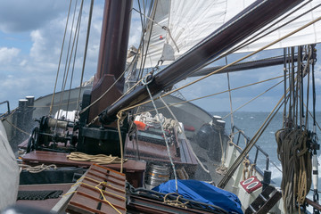 Spray thrown up by the bow of a historical sailing ship seen from deck