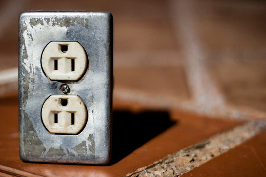 Closeup of an isolated electric plug double socket on the floor. Vintage south american type B socket. Copyspace.