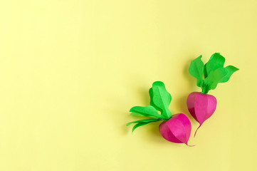 Two paper radishes on a yellow background