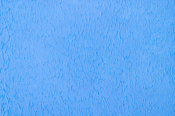Plastered concrete wall, painted in bright blue, decorative surface texture.
