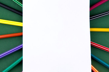 School office supplies stationery on a green background desk with white paper above copy space. Back to school concept.