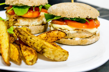  Salmon burger with rustic potatoes and rucula leaves.
