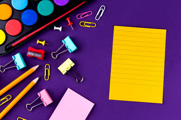 School office supplies stationery on a purple background desk with copy space. Back to school concept