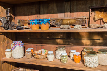 Fototapeta na wymiar Shelves with jars of seeds and jars of honey next to honeycombs.