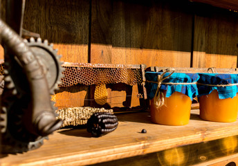 Shelves with jars of seeds and jars of honey next to honeycombs.