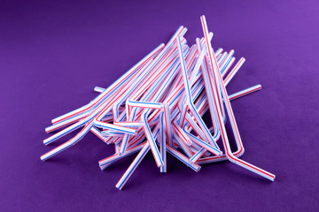 Coctail plastic tubes on blue purple background. Environmental concept. Ban single use plastic campaign. Copy space for text