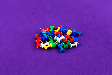 School office colored pins buttons isolated on purple background close up