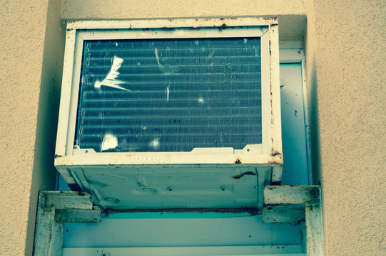 Old bad broken rectangular substandard rusty air conditioner for cooling air in summer