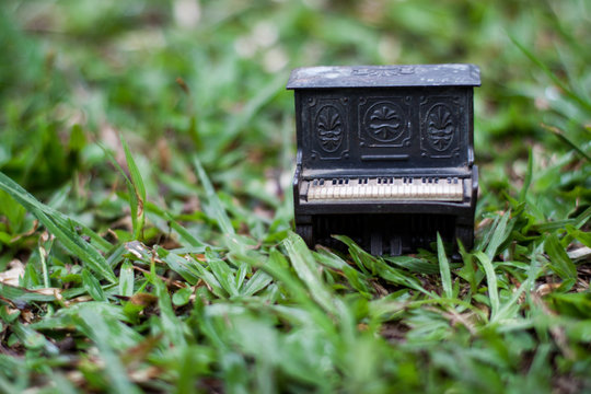 Closeup of a vintage mini piano on a grass field. Isolated piano on grass background. Music and artistic inspiration. Isolated with copyspace.