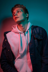 Fashion photo portrait of a young male model trendy fashionable urban style in studio on color gel background
