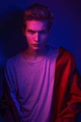 Fototapeta premium Fashion photo portrait of a young male model trendy fashionable urban style in studio on color gel background