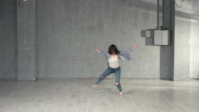 Young woman performing modern dance. Beautiful caucasian girl performs contemporary dance in modern studio.
