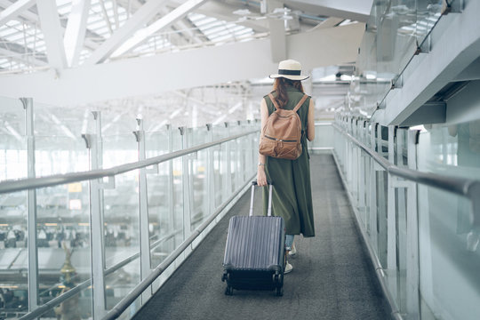 Asian woman traveler walking dragging luggage to travel to the airport in time to board the plane
