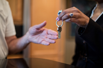 A female realtor hands over the keys to a new home to her client, an elderly man.