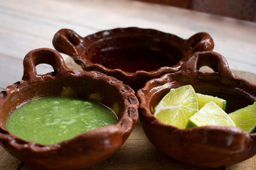 Salsa picante verde, salsa de chile de árbol y limones en cazuelas de barro son indispensables como complemento indispensable en la comida mexicana