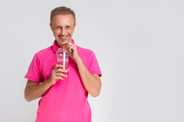 Portrait of Happy Smiling Caucasan Blond Man Holding Cup With Smoothie. Drinking Through Straw - Powered by Adobe
