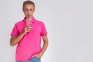 Portrait of Surprised Caucasan Blond Man Holding Cup With Smoothie. Drinking Through Straw. - Powered by Adobe
