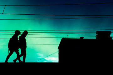two people walking on sky and wires background with silhouettes, house and stripes above them