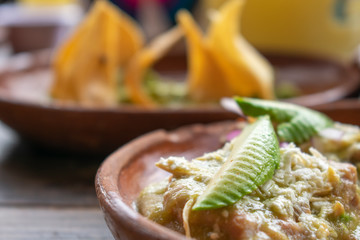 Comida mexicana: chilaquiles verdes con queso y aguacate en plato de barro