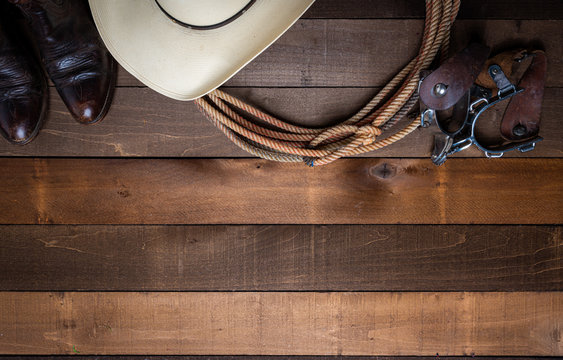 American Cowboy Items incluing a lasso spurs and a traditional straw hat on a wood plank background