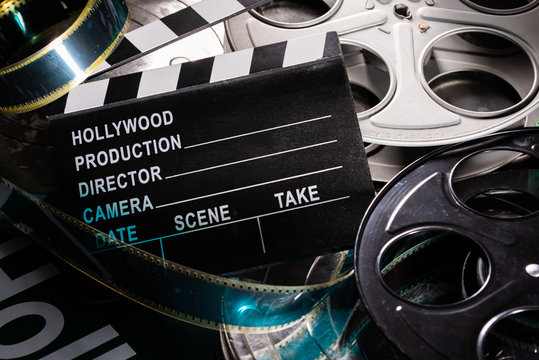 Movie clapper and film reel on a wooden background