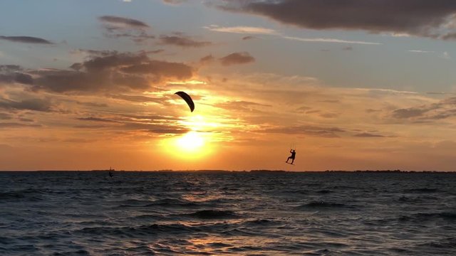 Kite surfing at sunset on the ocean with waves and jumps