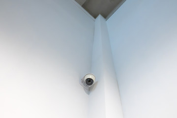 a security camera installed at the edge of a white wall.