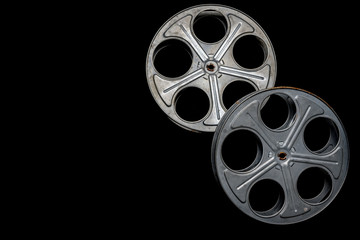 Two vintage film reels on a black background with copy space