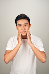 Young Asian man touching his skin and feeling on white background