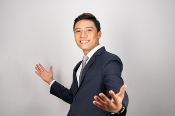 Portrait shot of cheerful young businessman with spread open arms  and smiling while standing at isolated white background.