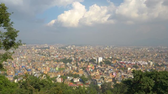 SLOW MOTION: Panoramic shot of Kathmandu from the famous Swayambhunath temple. Beautiful blue sky spans above a city in Nepal. Colorful buildings of a residential neighborhood in a poor Asian city.