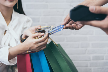 Young Asian woman shopping online with credit card and NFC machine wifi reader.