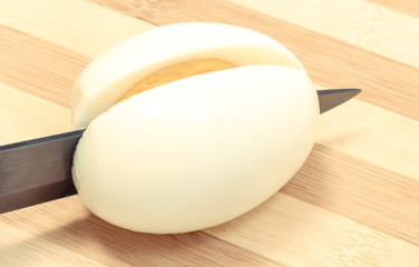 Kitchen knife cutting cooked egg on board