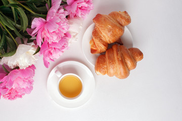 Breakfast for Valentines day with cup of tea, croissant, flowers on white table from above in flat lay style, seasonal springtime holiday background, blogger lifestyle