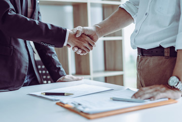Middle age Asian partner lawyers attorneys shaking hands after discussing a contract agreement done. - obrazy, fototapety, plakaty
