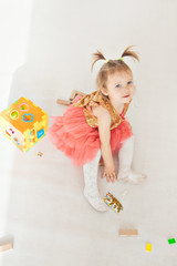 portrait of a little girl with tails on white background. Baby plays with toys