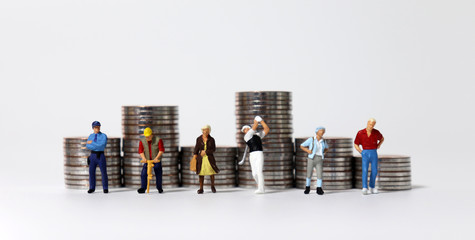 Coin stacks and various miniature people. The concept of the wage gap according to occupation.